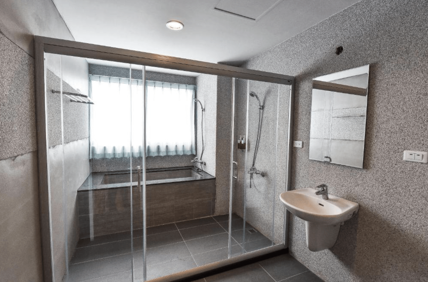 【台南安平住宿】我小時候設計旅店的衛浴空間，採乾濕分離設計，設有大型玻璃拉門，內部有淋浴設備與浴缸，窗邊自然光充足，整體風格簡約現代。