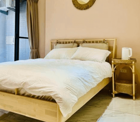 【虎尾住宿】日日見宅的雙人房，配備木質雙人床與藤編床頭櫃，上方掛有圓形藤編裝飾鏡，整體風格自然溫馨，充滿南洋度假感。