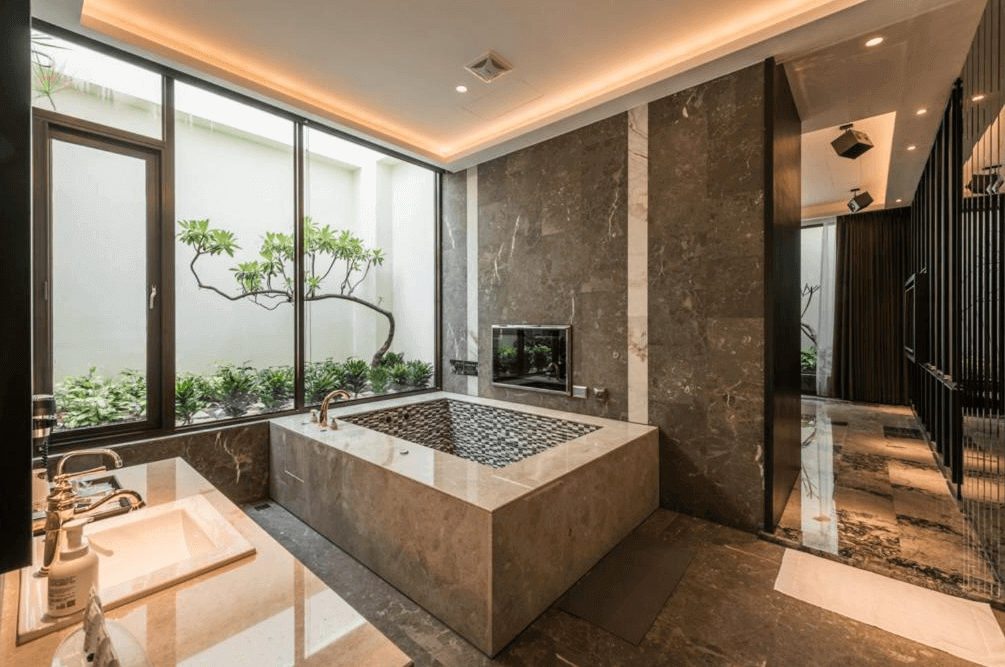 【員林住宿】棕櫚湖岸精品旅館的私人湯屋，擁有大型石材泡湯池，並配有高級洗手台與鏡面設計。空間以深色大理石鋪陳，搭配落地窗景，可直接欣賞庭院綠植，提供沉浸式的度假享受，結合奢華與自然景觀。