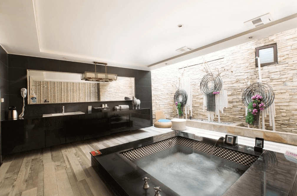 【員林住宿】楓采時尚汽車旅館的高級湯屋設計，浴池採用黑色石材，搭配大型落地窗，可直接欣賞室外庭園造景。黑色洗手台與鏡面設計展現現代感，牆面裝飾有金屬質感藝術裝飾，整體空間時尚且高雅。