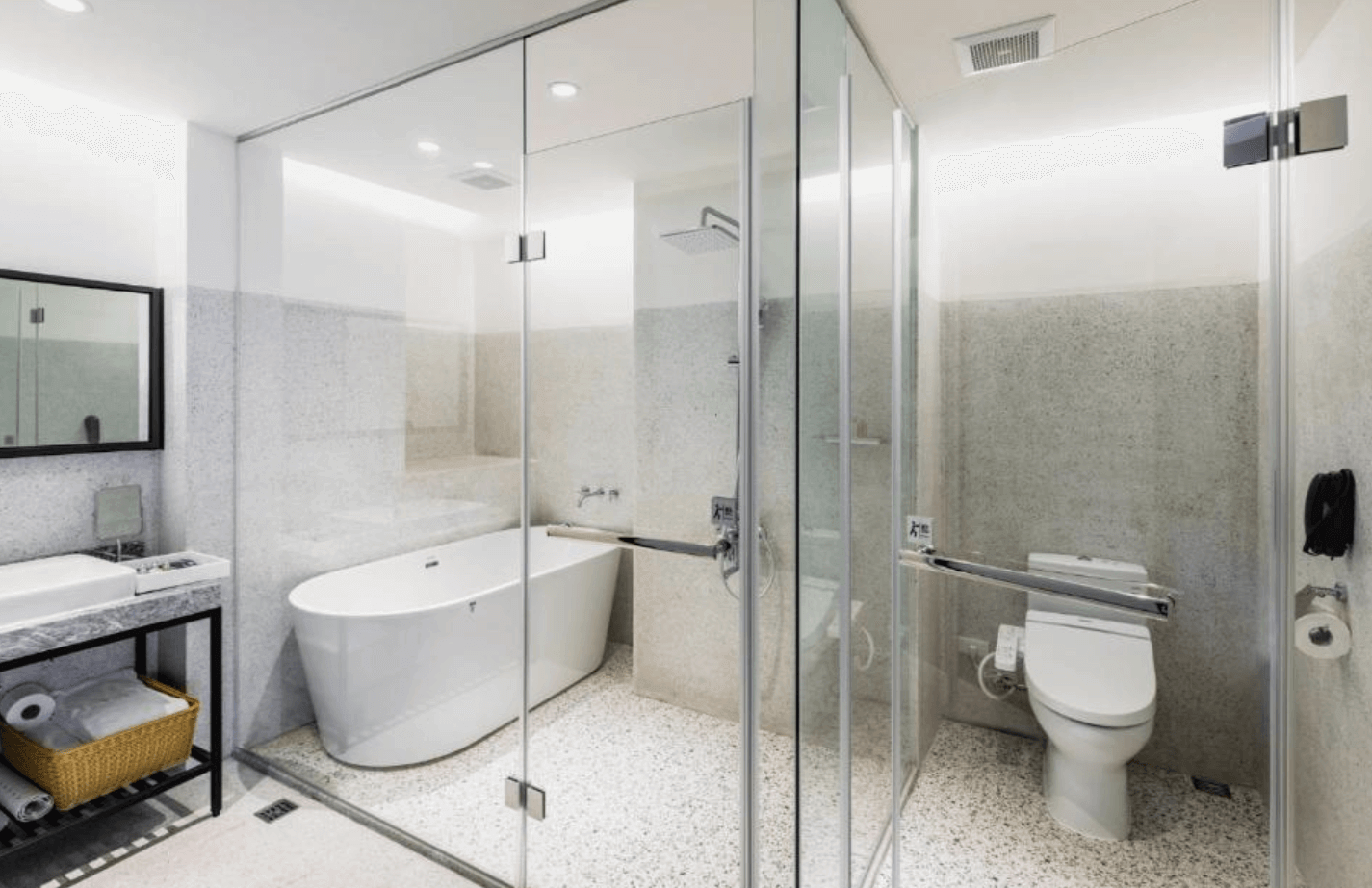 【台南安平住宿】福爾摩沙遊艇酒店的高質感衛浴空間設計，設有獨立淋浴間、免治馬桶與圓弧形浴缸，採用全玻璃乾濕分離設計與大理石洗手檯，呈現時尚且功能齊全的衛浴環境。