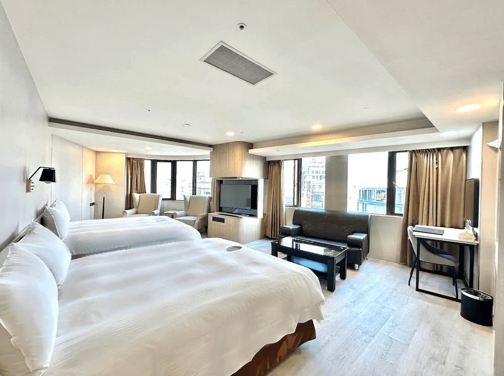 【斗六住宿】緻麗伯爵酒店的四人房型，房內設有兩張大床、皮質沙發區、電視與辦公桌，窗邊還有兩張高背單椅與落地燈，整體空間寬敞明亮，適合家庭或朋友同行入住。