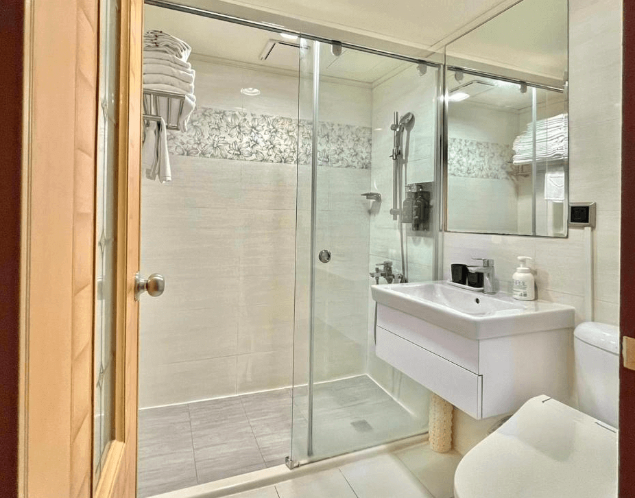 【斗六住宿】緻麗伯爵酒店的浴室空間，採乾濕分離設計，設有大片玻璃拉門與白色洗手台，牆面搭配花紋磁磚裝飾，整體明亮整潔，備品齊全，適合親子家庭使用。