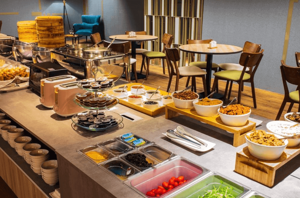 【斗六住宿】華安大飯店的自助早餐區，提供多樣化中西式餐點，包括小菜、炸物、蒸籠點心、生菜沙拉與果醬吐司，環境明亮乾淨，座位區寬敞舒適，適合家庭與團體用餐。