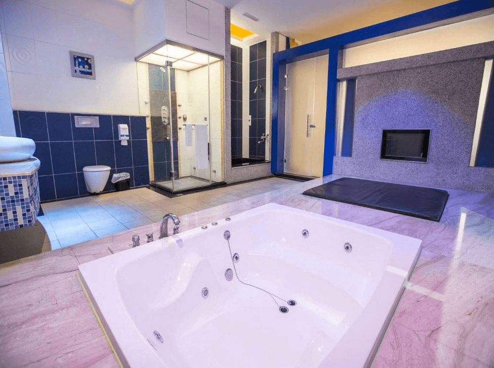 【斗六住宿】觀月商務休閒旅館的豪華浴室，空間內設有大型按摩浴缸、乾濕分離淋浴間、雙人床墊區，牆面採用藍白色調搭配馬賽克磁磚，整體風格清爽又具時尚感。