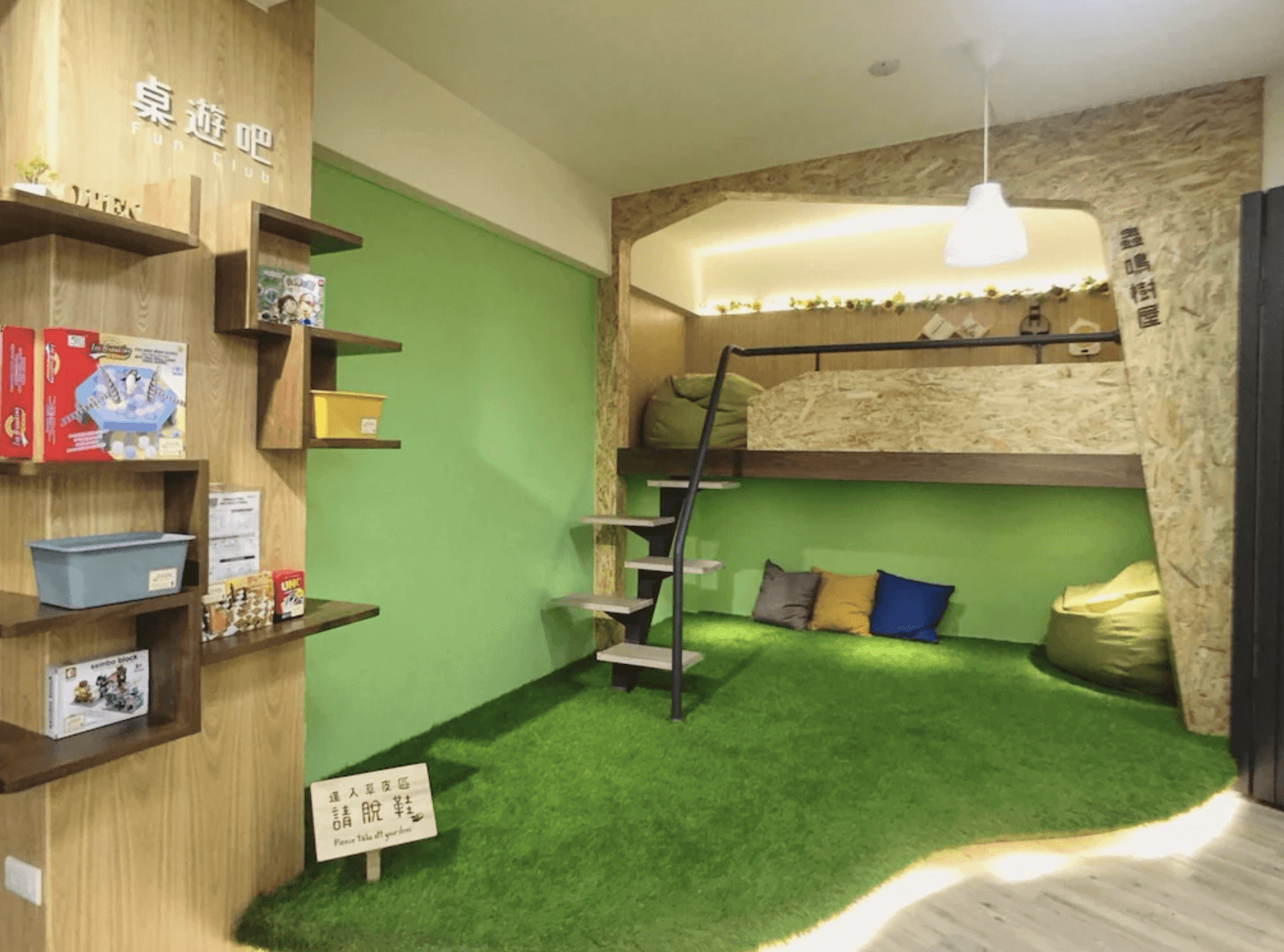 【逢甲夜市住宿】逢甲葉綠宿旅館內部的「桌遊吧」區域設計富有創意,鋪設草皮地毯,設有上下層的特色休憩空間,牆上擺放多種桌遊,適合親子或朋友聚會休閒使用。