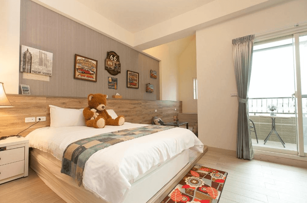 【五結住宿】D3經典民宿的美式復古風格雙人房，搭配仿舊車牌與老車掛畫裝飾，床上擺有大熊布偶，陽台外設有小桌椅，空間溫馨舒適，適合情侶入住。