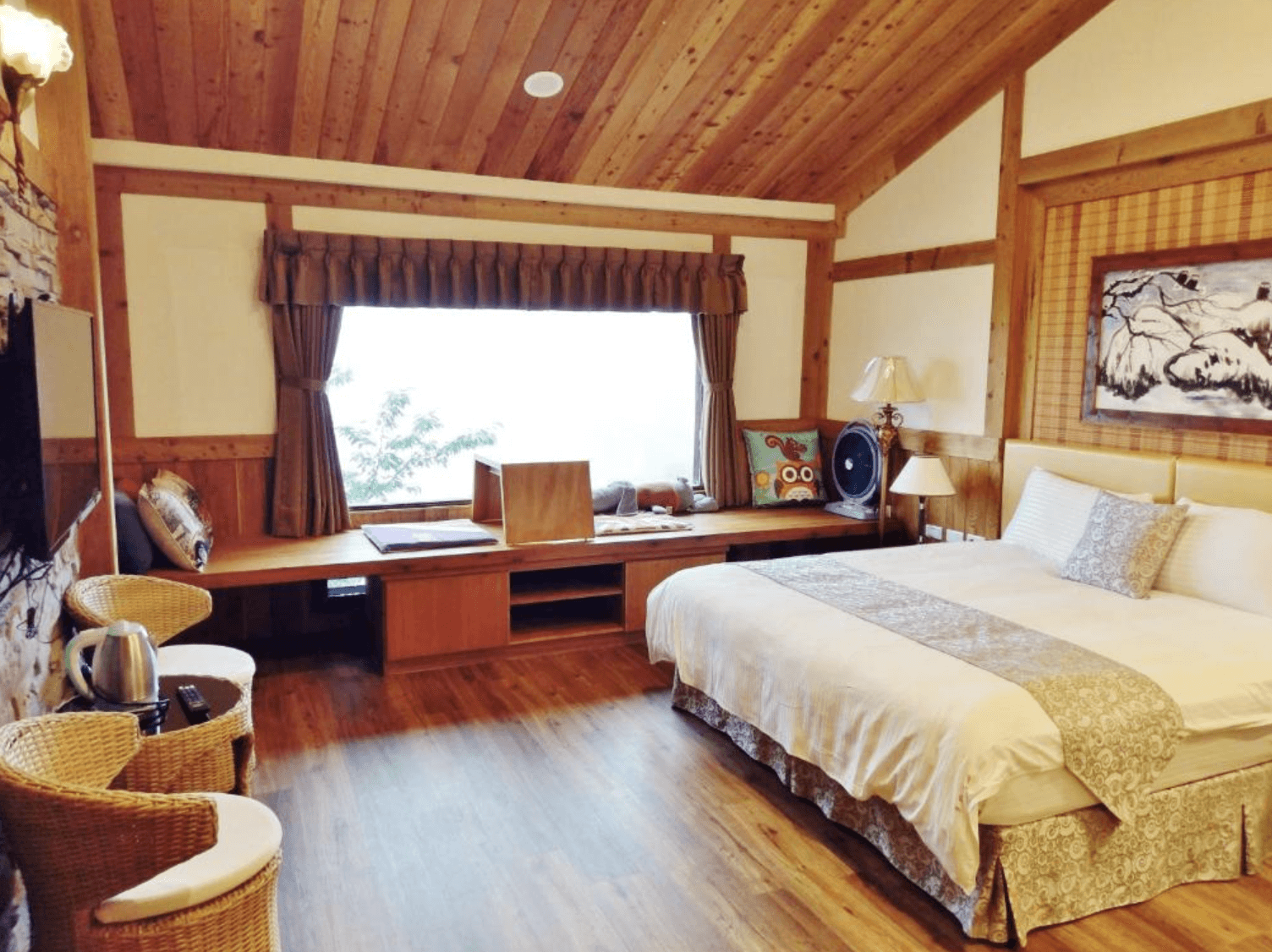 【清境農場住宿】事外桃源渡假山莊原木元素的溫馨雙人房，設有舒適雙人床與大片窗邊臥榻空間，窗外可眺望山林景緻，室內擺設藤編椅與復古風檯燈，整體氛圍典雅寧靜，充滿自然質感。