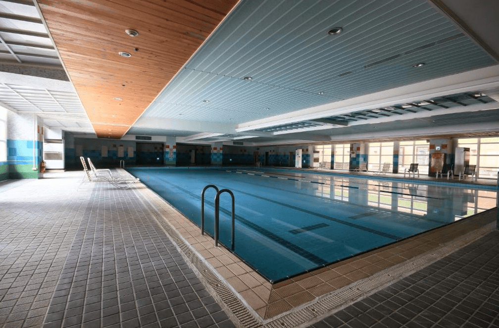 【彰化飯店】亞太鹿港渡假村室內游泳池，配有標準泳道與休息躺椅，天花板設計現代並有充足採光。