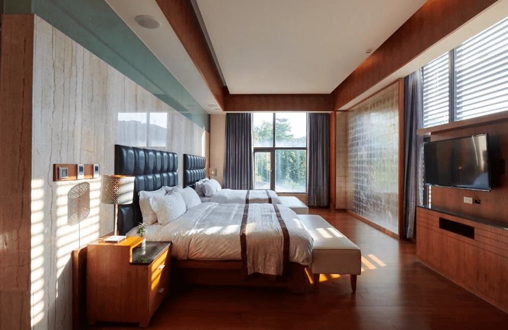 【關子嶺溫泉】“白河住宿”儷景溫泉會館的四人房，設有兩張雙人床與大片落地窗，自然光充足，房內配有電視、木質家具與簡約裝潢，空間寬敞舒適。
