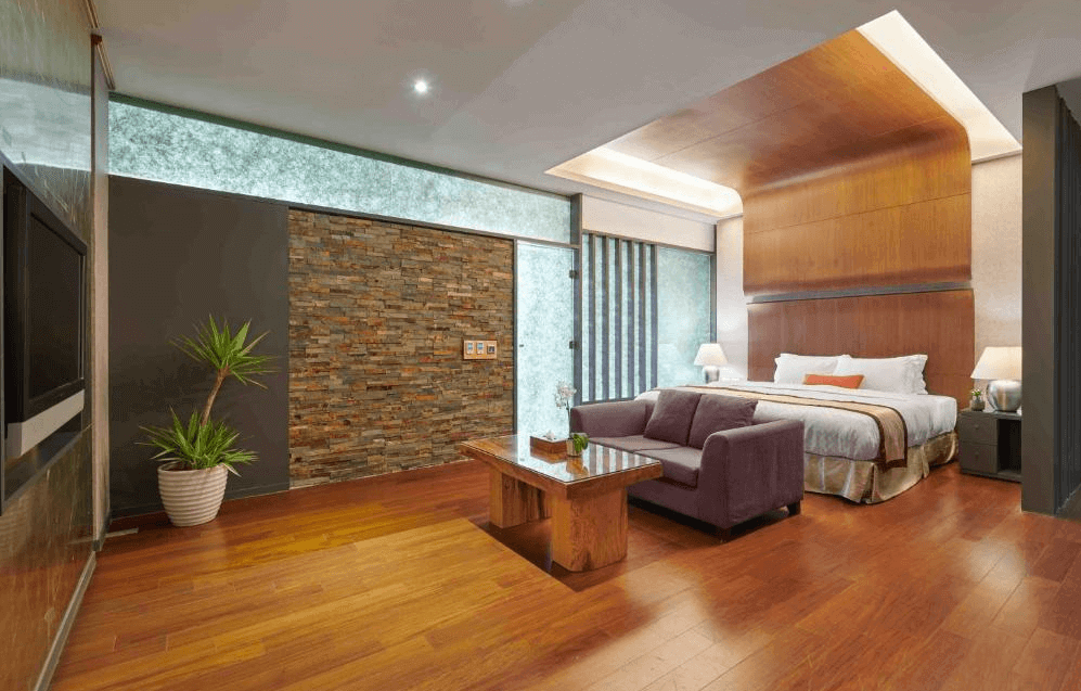 【關子嶺溫泉】“白河住宿”儷景溫泉會館的雙人套房擁有高質感木地板與沉穩色調，房內設有沙發與茶几休憩區，牆面為石材與木飾板設計，營造溫暖沉穩氛圍。