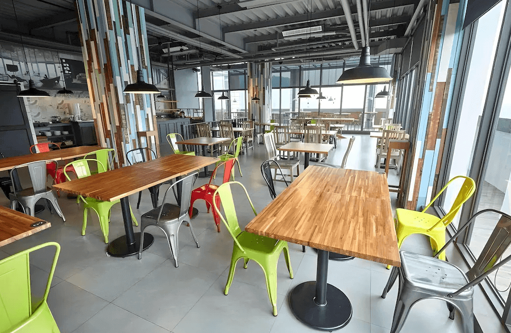 【關子嶺溫泉】儷景溫泉會館的開放式用餐區設有大片落地窗與多張木桌搭配繽紛金屬椅，採工業風設計風格，空間明亮且富現代感。