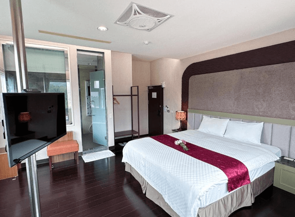 【關子嶺溫泉】“白河住宿”儷泉溫泉館的現代簡約風格雙人房，配有一張大床、深色木地板與紫紅色床旗，房內設有電視、開放式衣架與乾濕分離浴室空間。