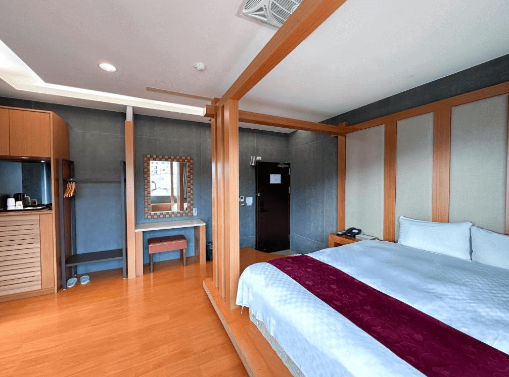 【關子嶺溫泉】“白河住宿”儷泉溫泉館的溫馨木質設計雙人套房，設有大床、穿衣鏡與木作化妝台，房內備有飲水設備與衣物收納空間，整體氛圍舒適放鬆。