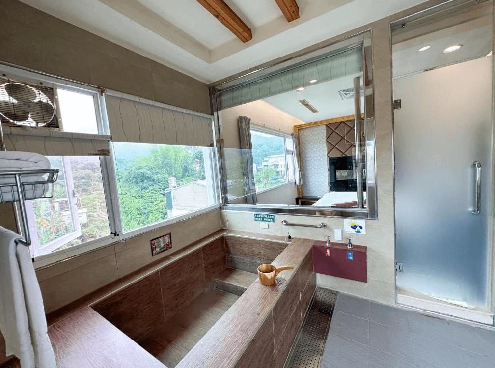 【關子嶺溫泉】儷泉溫泉館採光良好的獨立溫泉浴池空間，設有木質湯池與大片窗景，可欣賞戶外山景，隔間玻璃可連通房內視野。