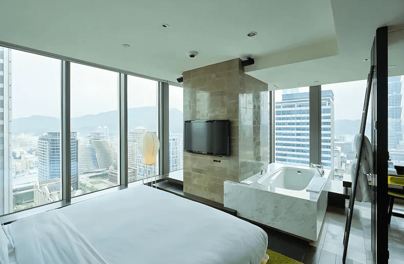 【台灣最貴飯店】台北W飯店的絕美市景高樓層客房，臥室與景觀浴缸共享大片落地窗視野，能一邊泡澡一邊欣賞台北101與城市天際線，展現奢華現代的設計品味。