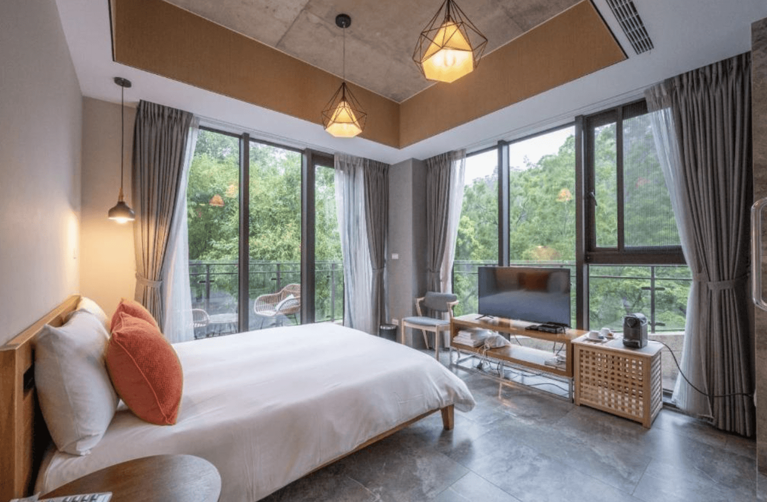 【三義住宿】向草語蟲民宿的雙人房，大片落地窗引入自然綠意，房內配有電視、咖啡機及簡約木質傢俱，光線明亮，空間舒適。