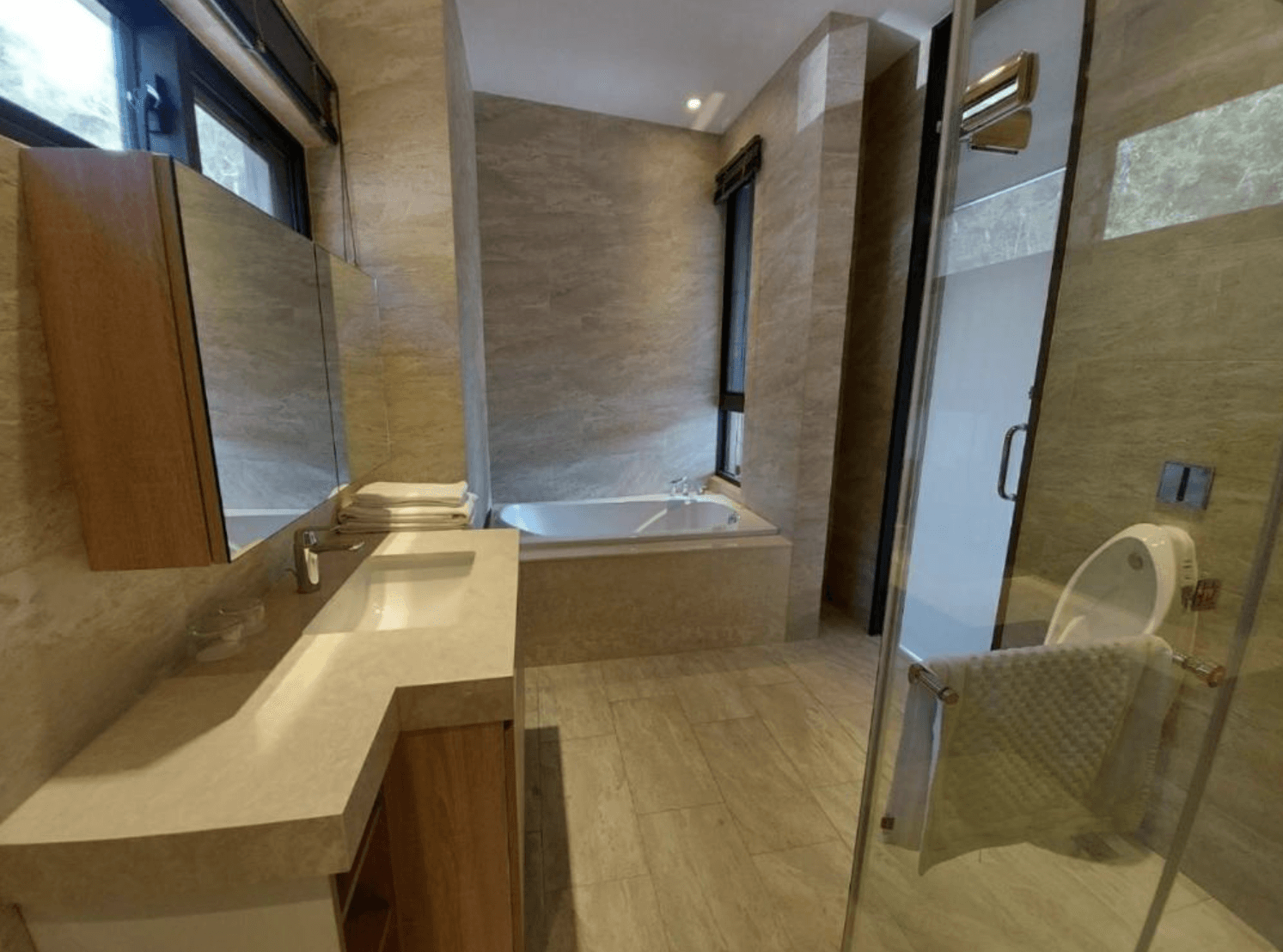 【三義住宿】向草語蟲民宿乾濕分離的大理石浴室，設有獨立浴缸與淋浴間，雙洗手台設計，整體以暖色系石材打造，空間明亮通風。