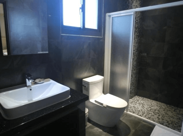 【彰化飯店】喜悅來行館浴室設施一覽，配有洗手台、馬桶與乾濕分離淋浴間，整體以深灰色磁磚搭配簡約風格設計。