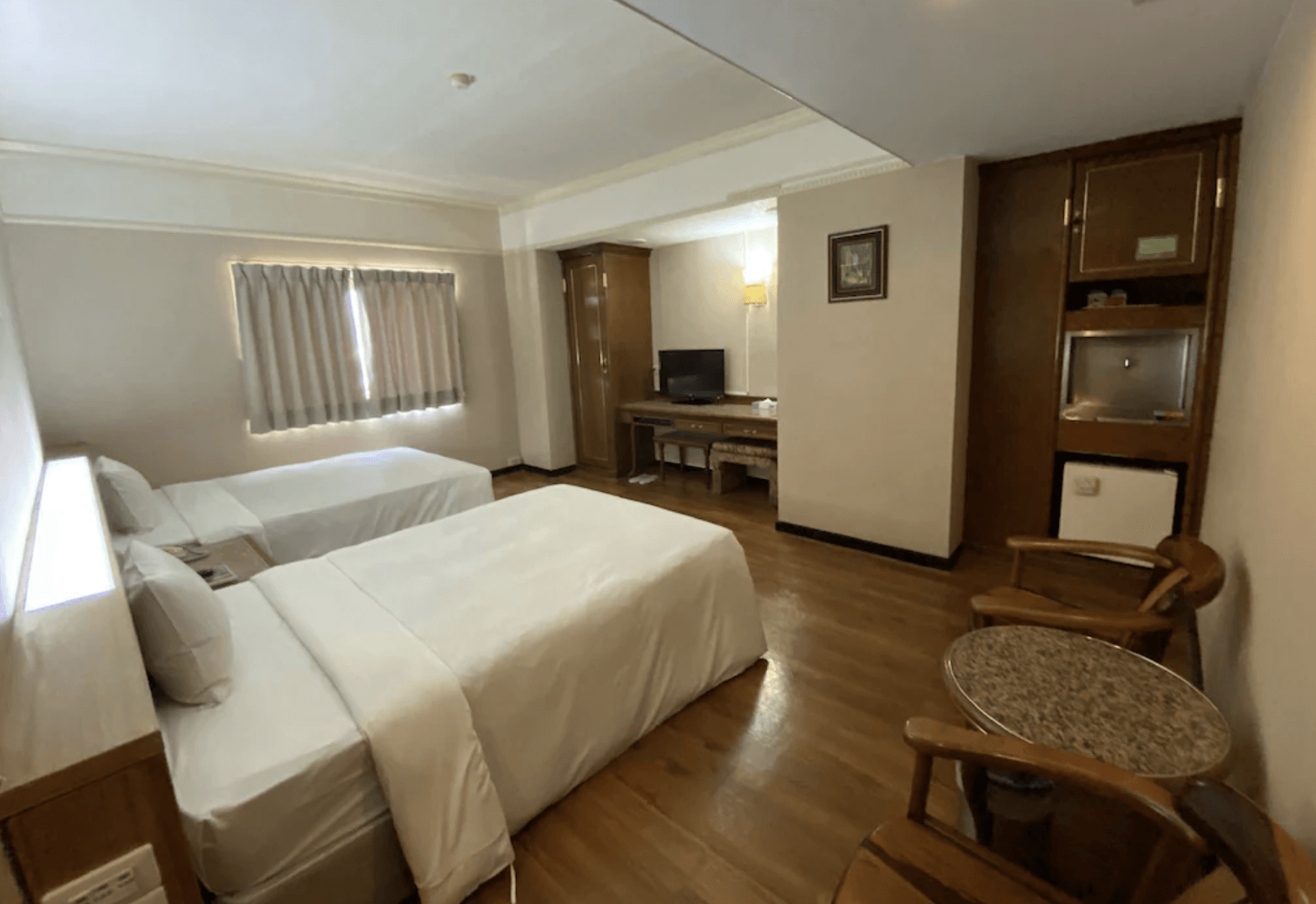 【東港住宿】大鵬灣大飯店的雙床客房，設有兩張單人床、木質地板與基本家具，電視、衣櫃、書桌與冰箱一應俱全，適合親子或朋友入住。