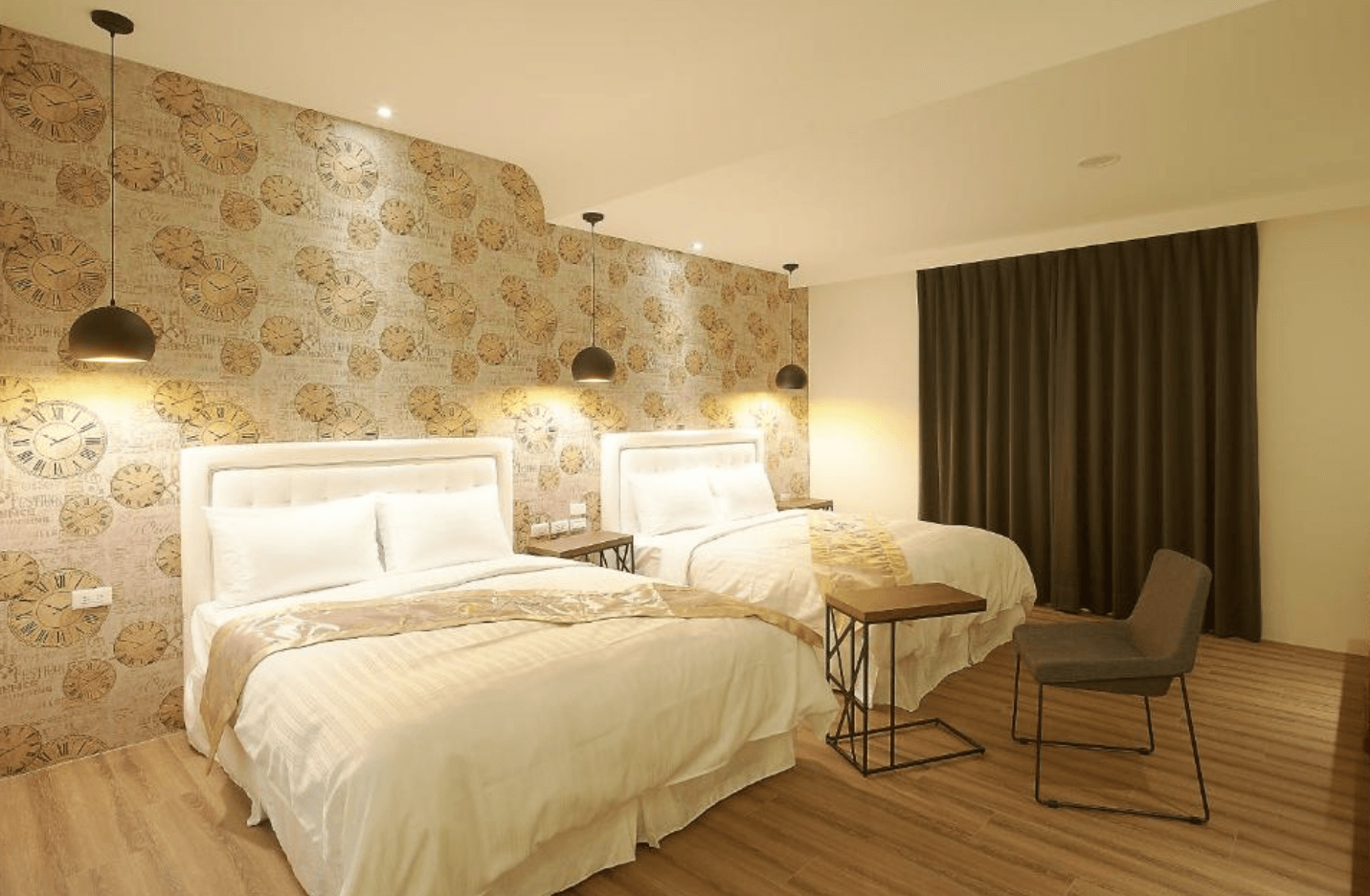 【東港住宿】大鵬灣瞭望台民宿的房間設有兩張雙人床，背景牆以復古鐘錶圖案裝飾，暖黃色燈光與吊燈營造柔和氛圍，適合親子或多人入住。