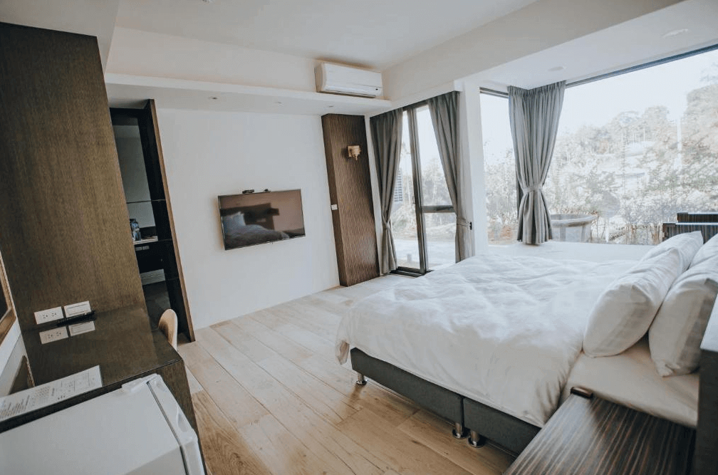 【瑞里民宿】山間茶墅民宿的雙人房，設有舒適的雙人床、電視、書桌及沙發區，房間明亮寬敞，可欣賞戶外山林景致。