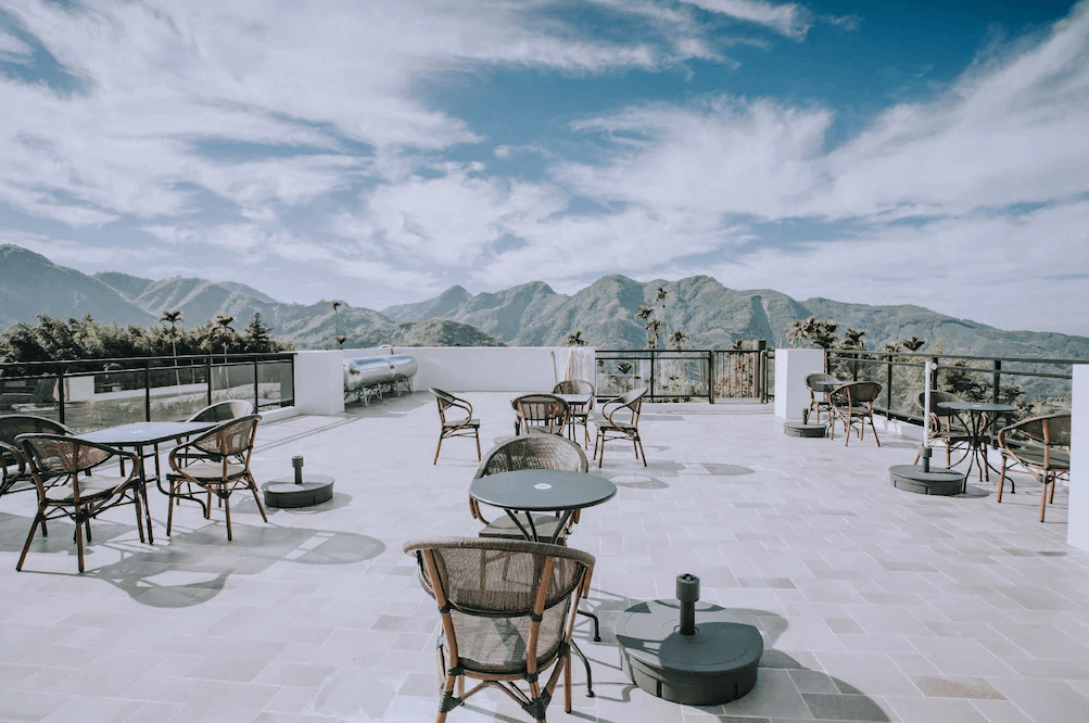 【瑞里民宿】山間茶墅民宿高處的開放式景觀露台，擺放數組桌椅，可遠眺壯麗山景與藍天白雲，適合下午茶與放鬆賞景。