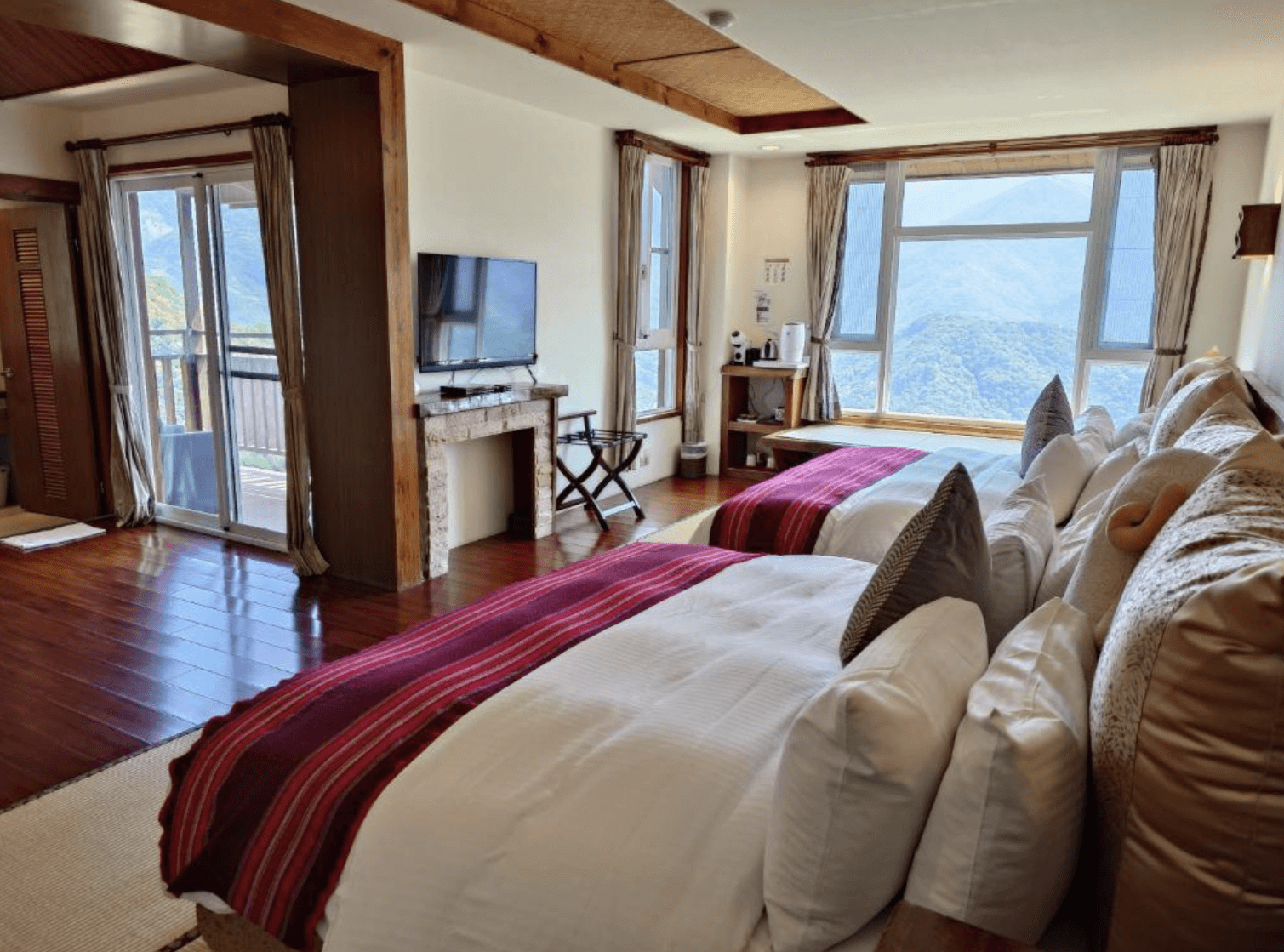 【清境農場住宿】愛薰閣會館從房內角度俯瞰窗外山景，房內設備包括液晶電視、小冰箱與泡茶區，空間寬敞舒適。