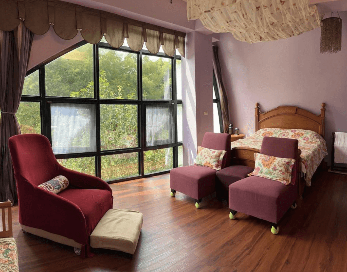 【三義住宿】慕哲哈比屋的溫馨房型，大面積拱形窗引入自然光，房內設有木質床架、紅酒色貴妃椅及滾輪椅凳，整體風格溫暖雅致。