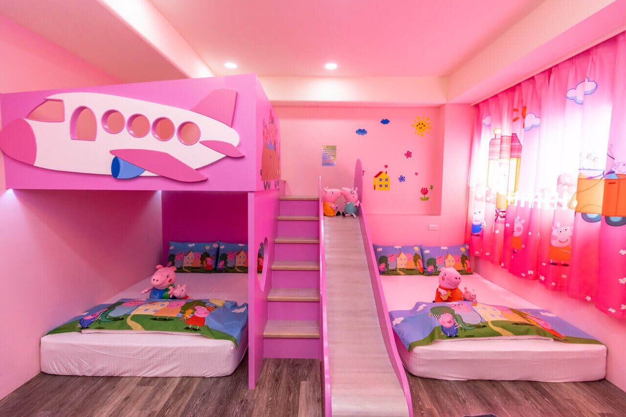 【五結住宿】掬月童心親子民宿的佩佩豬主題親子房，搭配飛機造型的上下舖與滑梯，床鋪及窗簾均有可愛的佩佩豬圖案，營造夢幻童話氛圍。