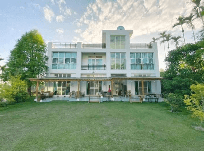 【瑞里民宿】朵麗絲森林的純白現代建築民宿，設有大面窗戶與陽台，周圍被綠樹環繞，前方為開闊的草地庭院，外觀清新自然。