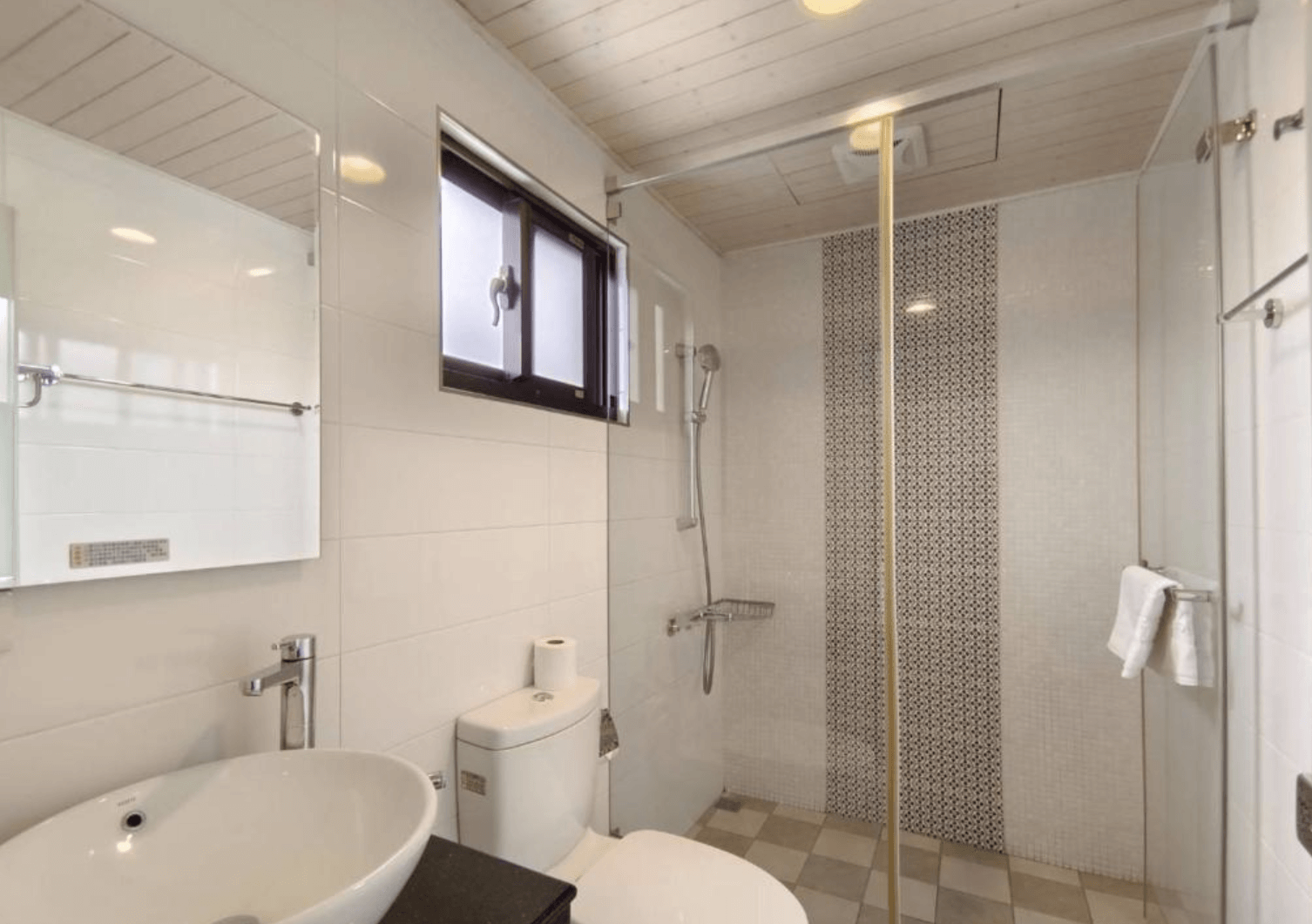 【東港住宿】東港幸福168民宿的白色牆面搭配灰白磁磚地板，設有玻璃淋浴間、馬桶與圓形檯面洗手盆，自然採光充足，整體乾淨清爽，兼具實用與現代感。