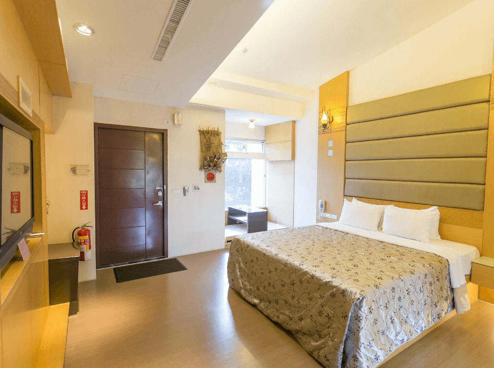 【關子嶺溫泉】“白河住宿”林桂園石泉會館的雙人房，設有大床與柔和燈光，牆面為皮革質感床頭板設計，空間寬敞明亮，窗邊設有休憩區。