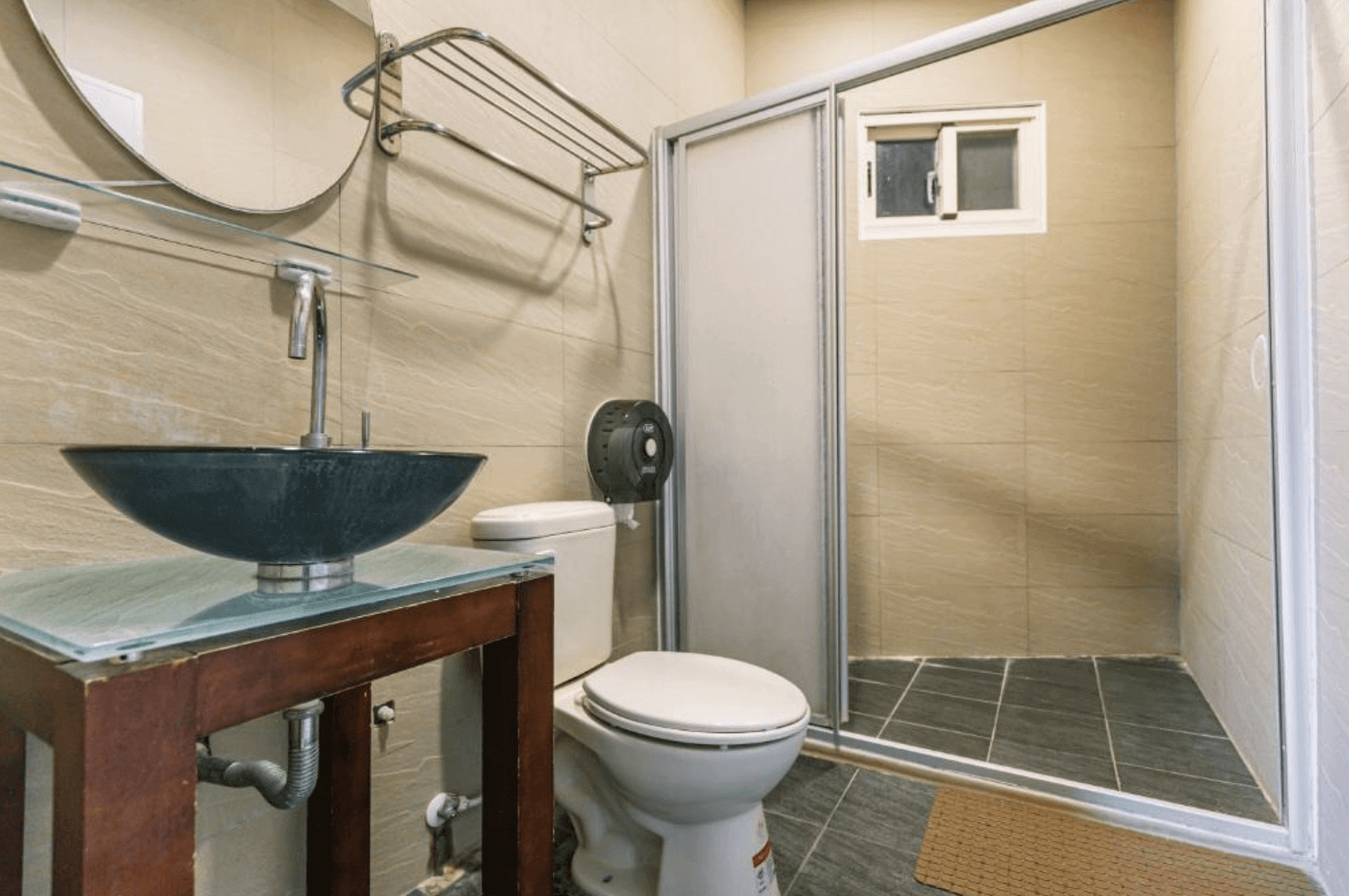 【清境農場住宿】清境之星樂活民宿的衛浴空間，設有玻璃檯面與造型洗手盆、馬桶及獨立淋浴間，牆面與地磚以米色與深灰色為主，整體乾淨整潔，提供基本盥洗設備。