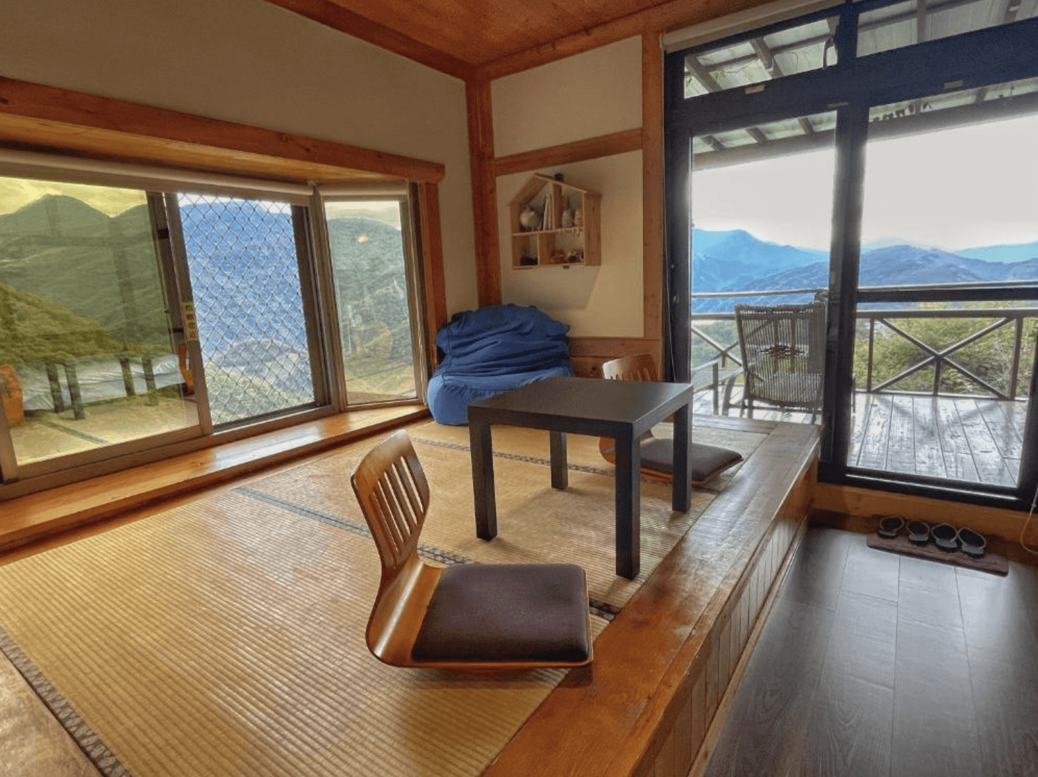 【清境農場住宿】清境天祥景觀民宿帶有濃厚日式風格的榻榻米空間，擺設兩張無腳椅與茶几，旁設有懶人沙發與木窗架展示，窗外連接觀景露台，可坐擁清境壯麗山景與陽光灑落的絕美畫面。