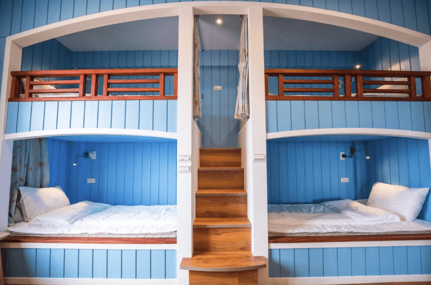 【清境農場住宿】清境繽紛農場的童趣風格的上下舖房型，以藍色木板牆面為主體，中央設有階梯可通往上舖床位，左右兩側各有兩個上下床鋪，搭配木欄杆與柔和燈光，營造出適合親子或團體入住的溫馨氛圍。