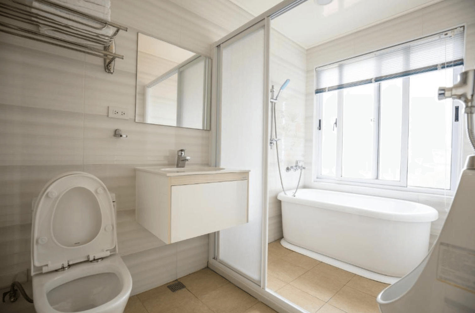 【清境農場住宿】清境繽紛農場的寬敞明亮的浴室，設有馬桶、洗手台與獨立的乾濕分離淋浴區，並備有一座獨立浴缸與大片窗戶，採光充足，整體設計簡潔清爽，以白色與米色調為主，提升放鬆舒適的沐浴體驗。