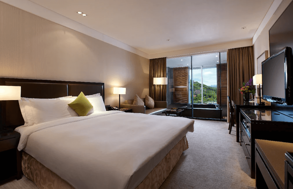 【蘇澳住宿】瓏山林蘇澳冷熱泉度假飯店的雙人房，配有一張大床、沙發區與落地窗，窗外設有專屬冷熱泉湯屋，可遠眺綠意山景，室內燈光柔和溫馨，設施完善。