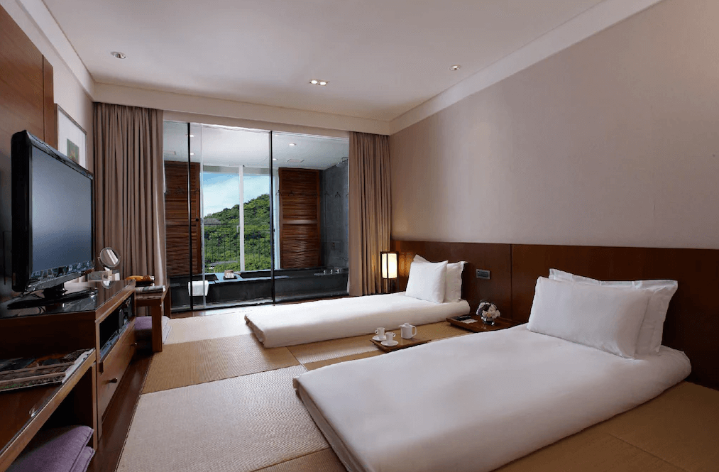 【蘇澳住宿】瓏山林蘇澳冷熱泉度假飯店的雙人房，榻榻米地板搭配兩張日式床墊，房內擺設茶具與液晶電視，落地窗外為專屬湯池與山林景觀，空間舒適靜謐。