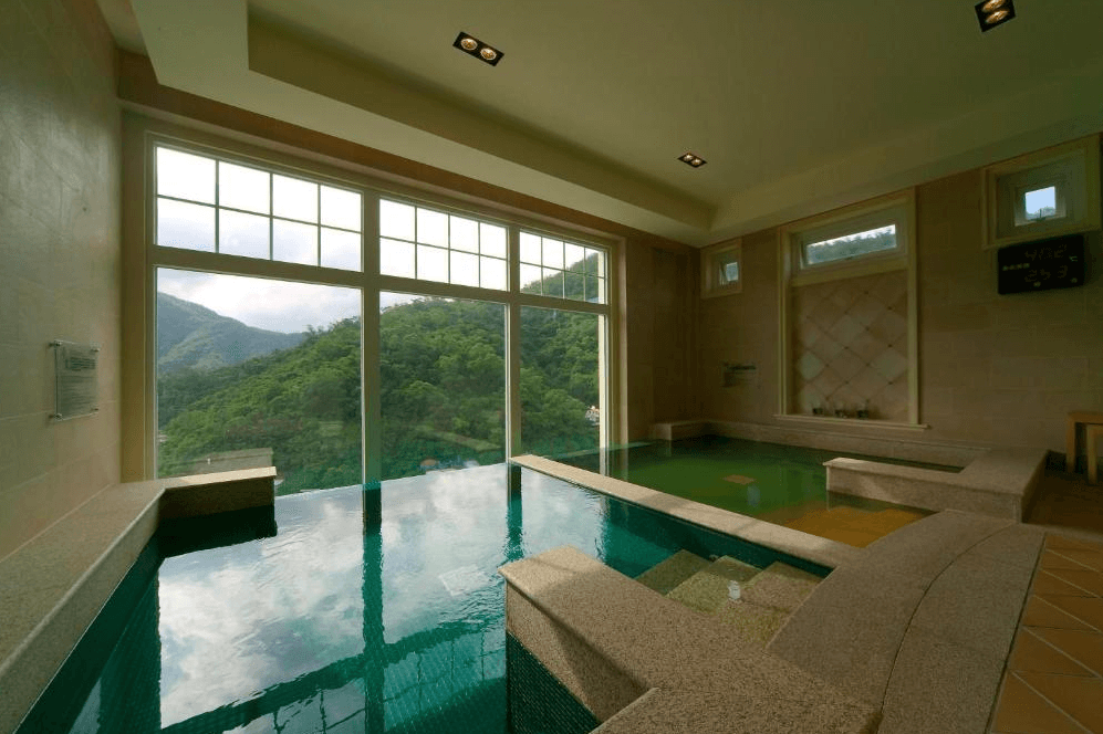 【蘇澳住宿】瓏山林蘇澳冷熱泉度假飯店的景觀大眾湯池空間，大片落地窗外即是綿延山景，室內設有冷泉與溫泉區域，採自然採光設計，提供放鬆身心的舒適泡湯體驗。