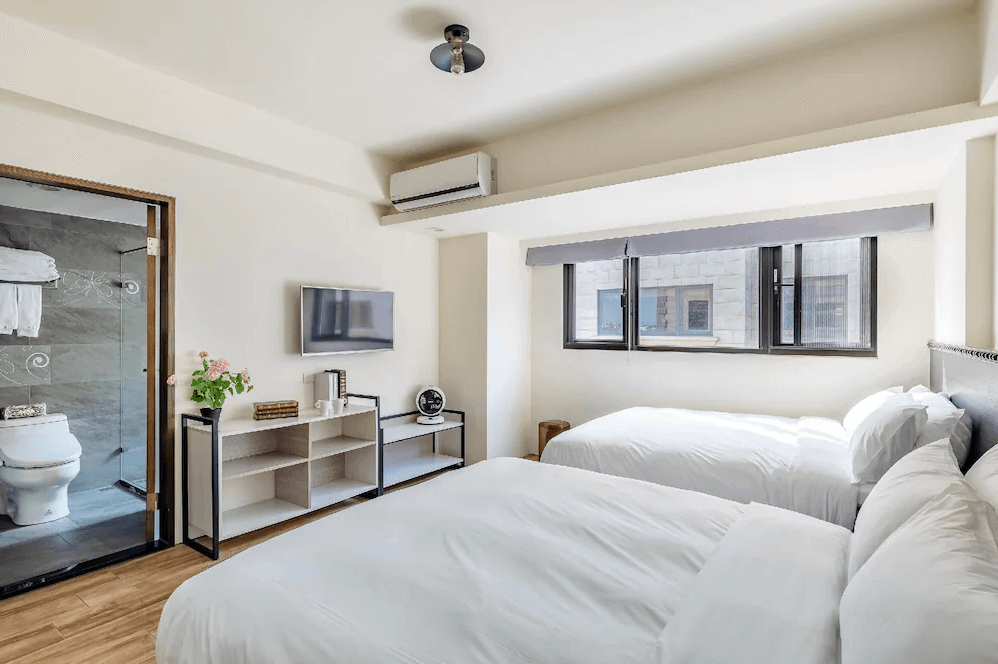 【五結住宿】米蘭穀堡的雙床客房，設有簡約收納櫃、電視與冷氣，衛浴位於房內，空間寬敞清爽，適合親子或雙人入住。