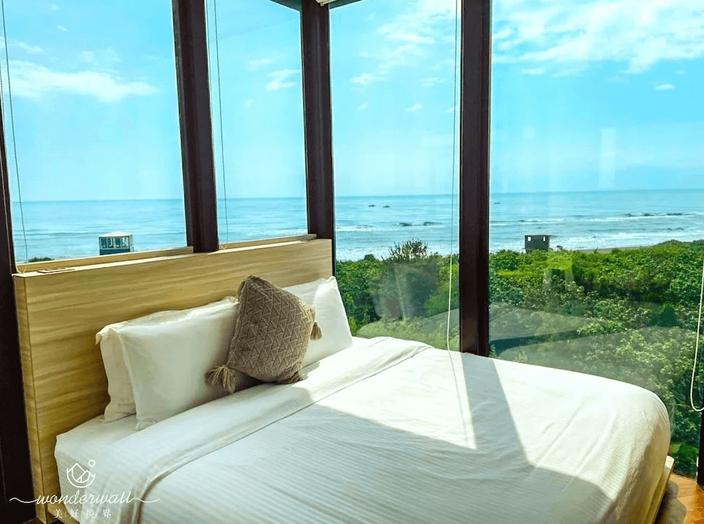 【五結住宿】美好境界民宿靠近落地窗的雙人床，三面環繞玻璃窗戶，可遠眺湛藍海景與綠意盎然的自然景觀，享受無敵海景第一排的放鬆氛圍。
