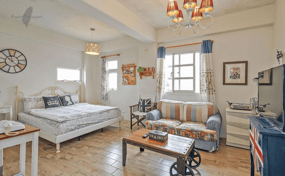【蘇澳住宿】蕾米斯莊園的英倫鄉村風雙人房，配有雕花鐵床、條紋沙發與復古時鐘裝飾，牆上掛有英國旗與典雅掛畫，整體風格溫馨活潑，融合文青與懷舊感。