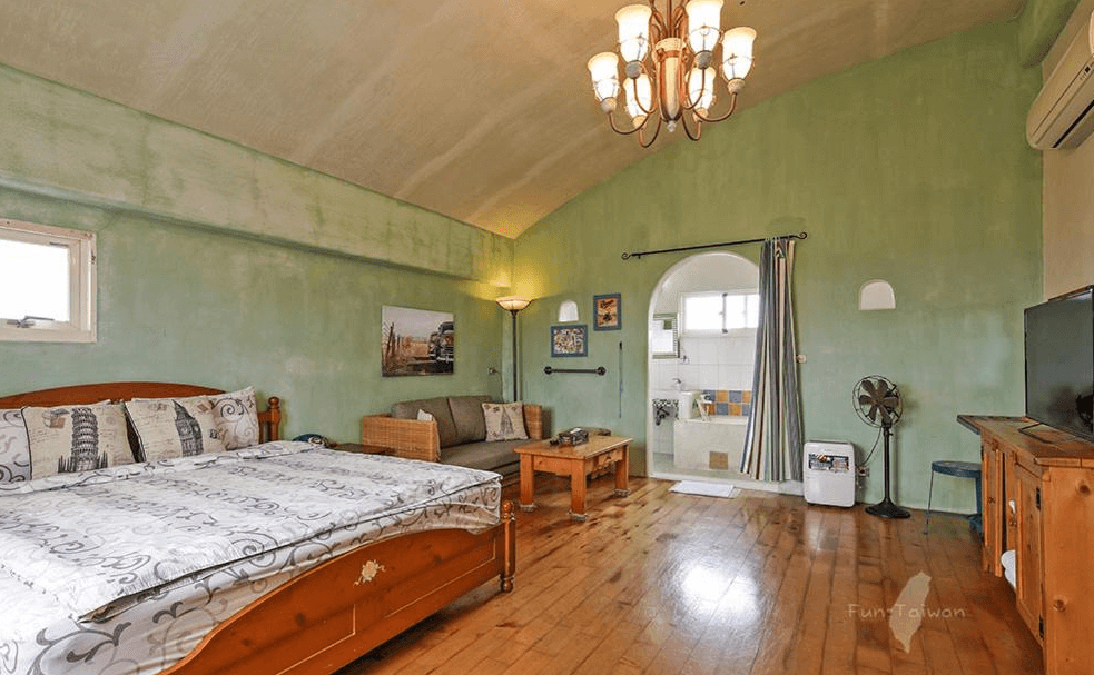 【蘇澳住宿】蕾米斯莊園的綠色牆面搭配木質家具的溫馨雙人房，空間寬敞明亮，設有木地板、舒適沙發與開放式衛浴空間，帶有地中海鄉村風格。