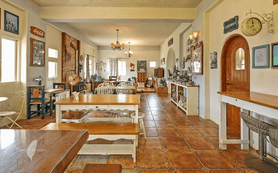 【蘇澳住宿】蕾米斯莊園的公共用餐空間，以溫潤磚紅色地磚與木質餐桌椅為主，牆上擺設多樣歐風裝飾與老件擺飾，整體空間充滿懷舊氛圍，適合悠閒用餐與拍照打卡。