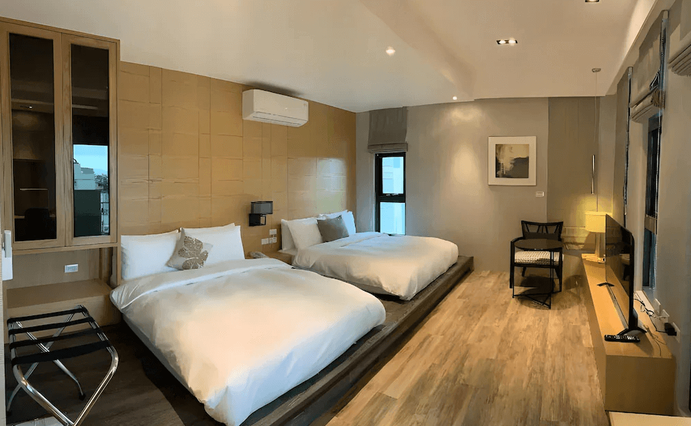 【五結住宿】藏闊渡假會館的雙床房型，採用溫潤木地板與木質牆面設計，配置兩張大床與電視、書桌、座椅，空間明亮舒適。