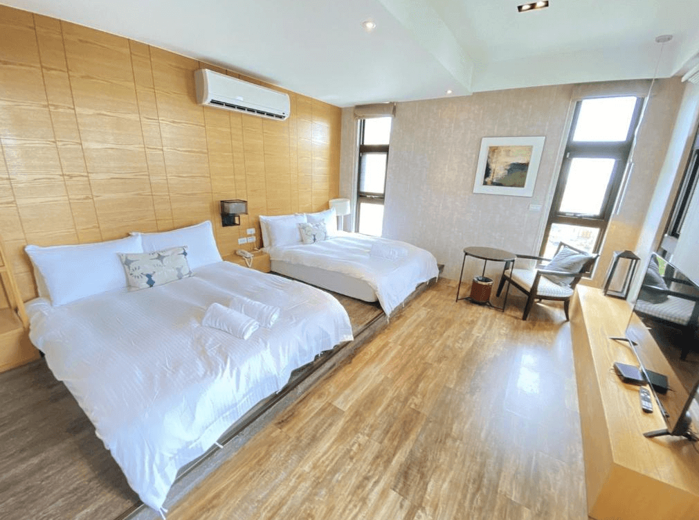 【五結住宿】藏闊渡假會館採光良好的雙床房型，牆面採原木紋設計，搭配大片落地窗與柔和燈光，房內設有電視與簡約家具，氛圍溫馨放鬆。