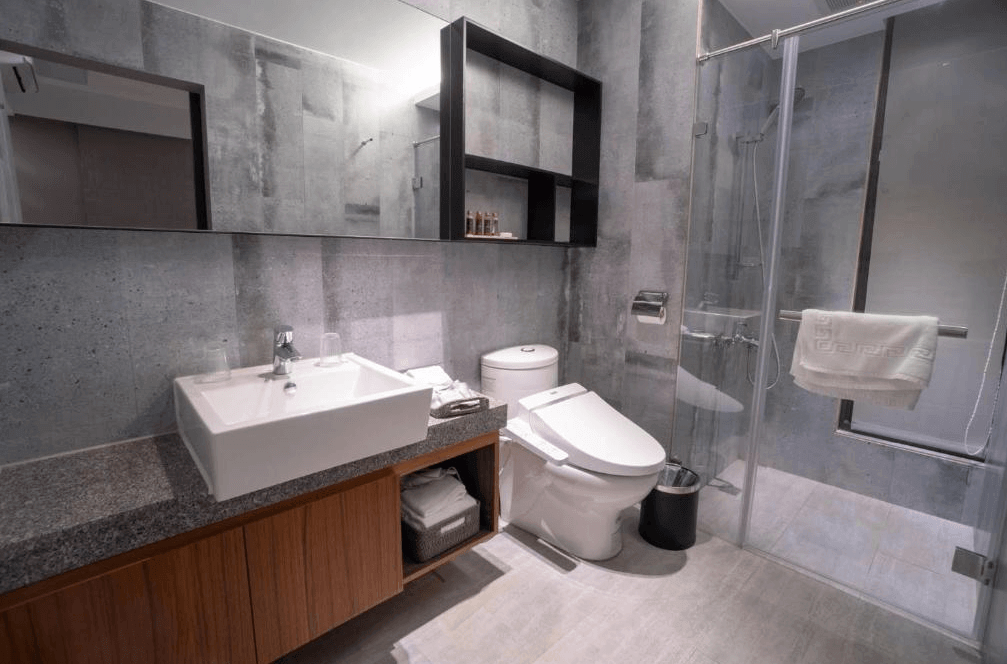 【五結住宿】藏闊渡假會館的現代衛浴空間，設有乾濕分離淋浴間、免治馬桶與方形洗手台，牆面以灰色石紋磁磚打造，整體潔淨俐落。