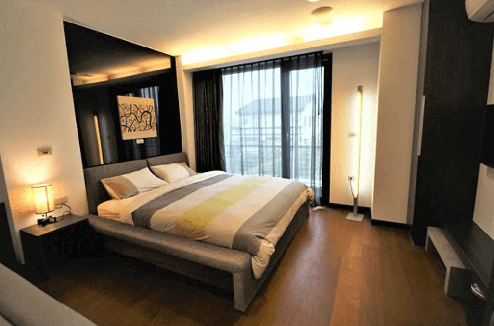 【五結住宿】設計師的家休閒民宿的雙人房，搭配灰色繃布床架與柔和光源，大片落地窗搭配紗簾營造自然採光，整體空間溫馨且具質感。