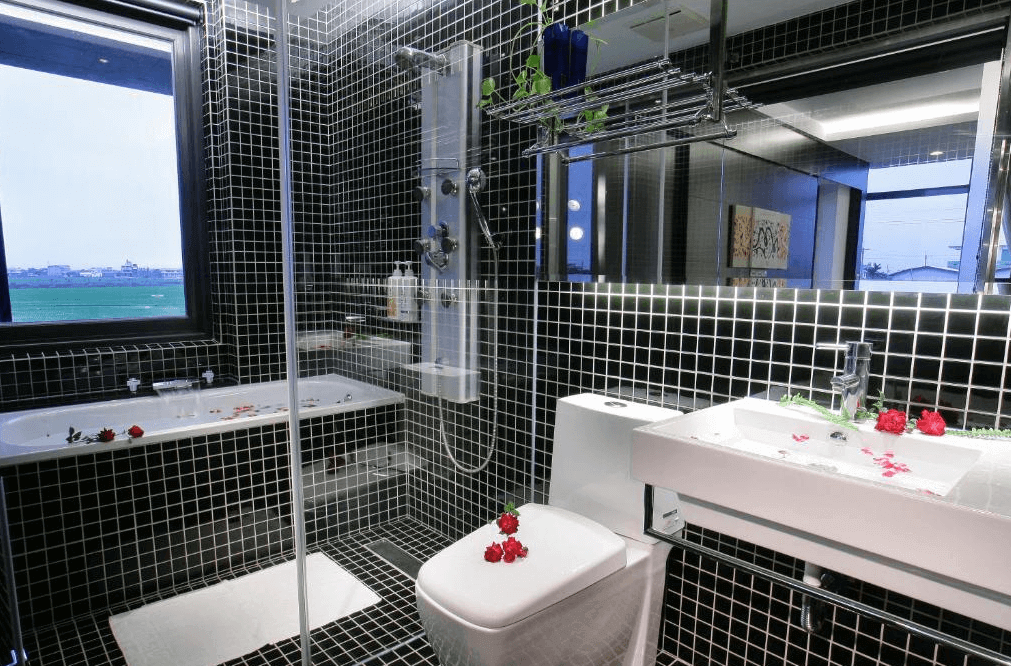 【五結住宿】設計師的家休閒民宿以黑色小方格磁磚打造的時尚衛浴空間，設有乾濕分離淋浴區與泡澡浴缸，窗外可眺望綠意田園景觀，整潔高雅。